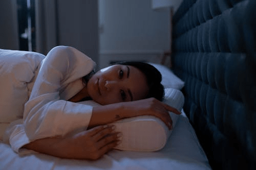 a woman trying to sleep on her bed