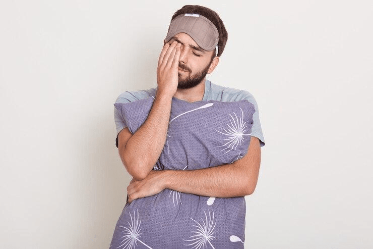 A man holding his pillow without wearing an actigraph watch