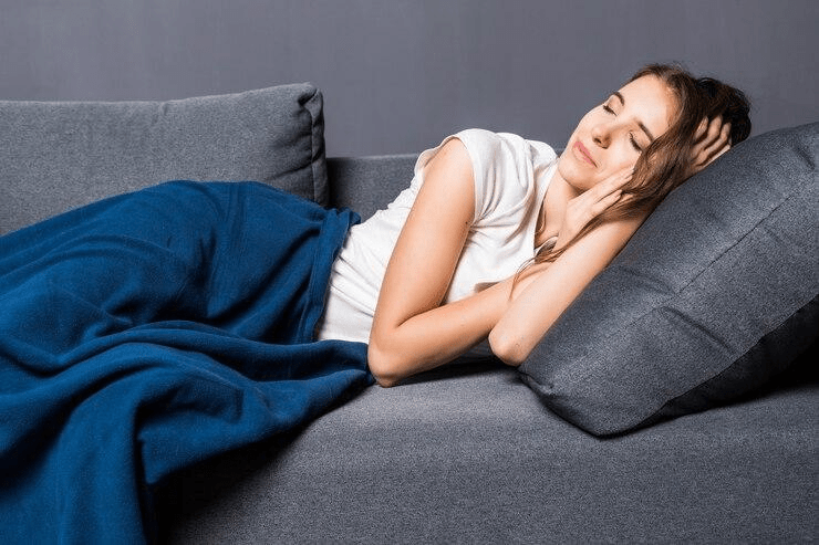 A woman trying to sleep on a couch while wearing an actigraphy device