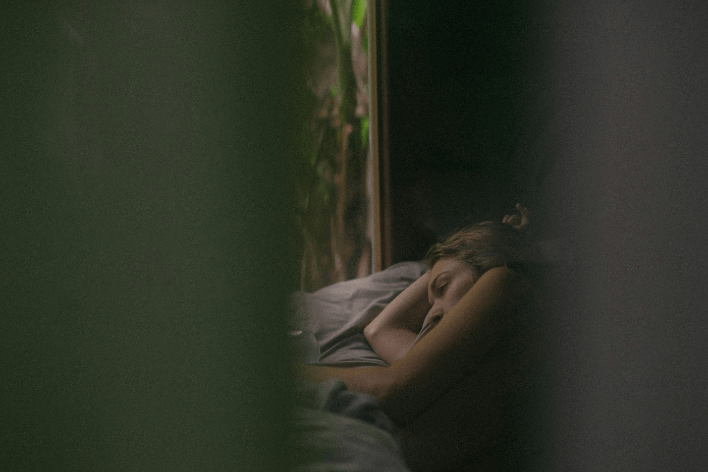 A woman trying to sleep in bed while wearing an actigraphy device