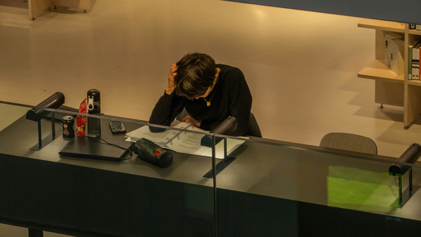a stressed worker going over a file while holding his head
