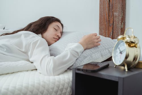 Person sleeping beside an alarm clock during sleep monitoring or sleep pattern observation